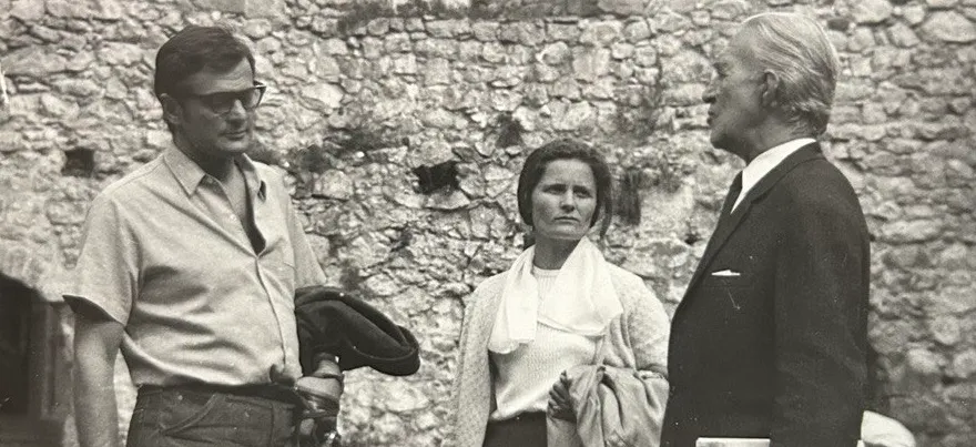 Arhivska crno-bela fotografija: Milica Mihajlović u razgovoru sa dvojicom muškaraca ispred kamenog zida